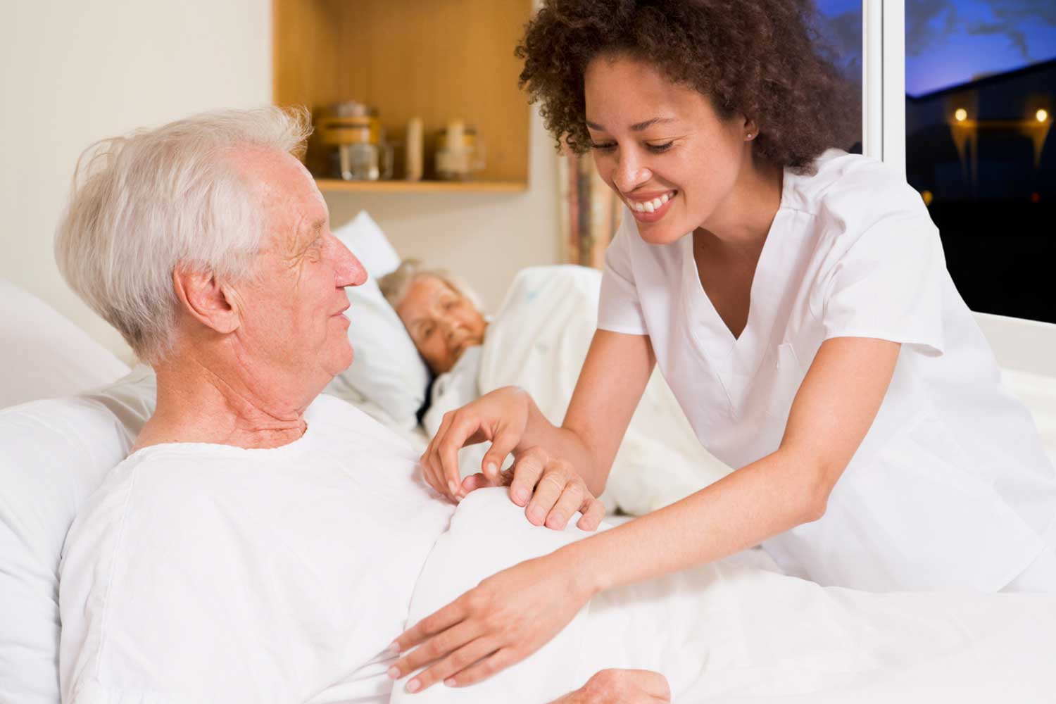 Hospice nurse caring for an elderly patient in bed, reflecting compassionate 24-hour hospice care.