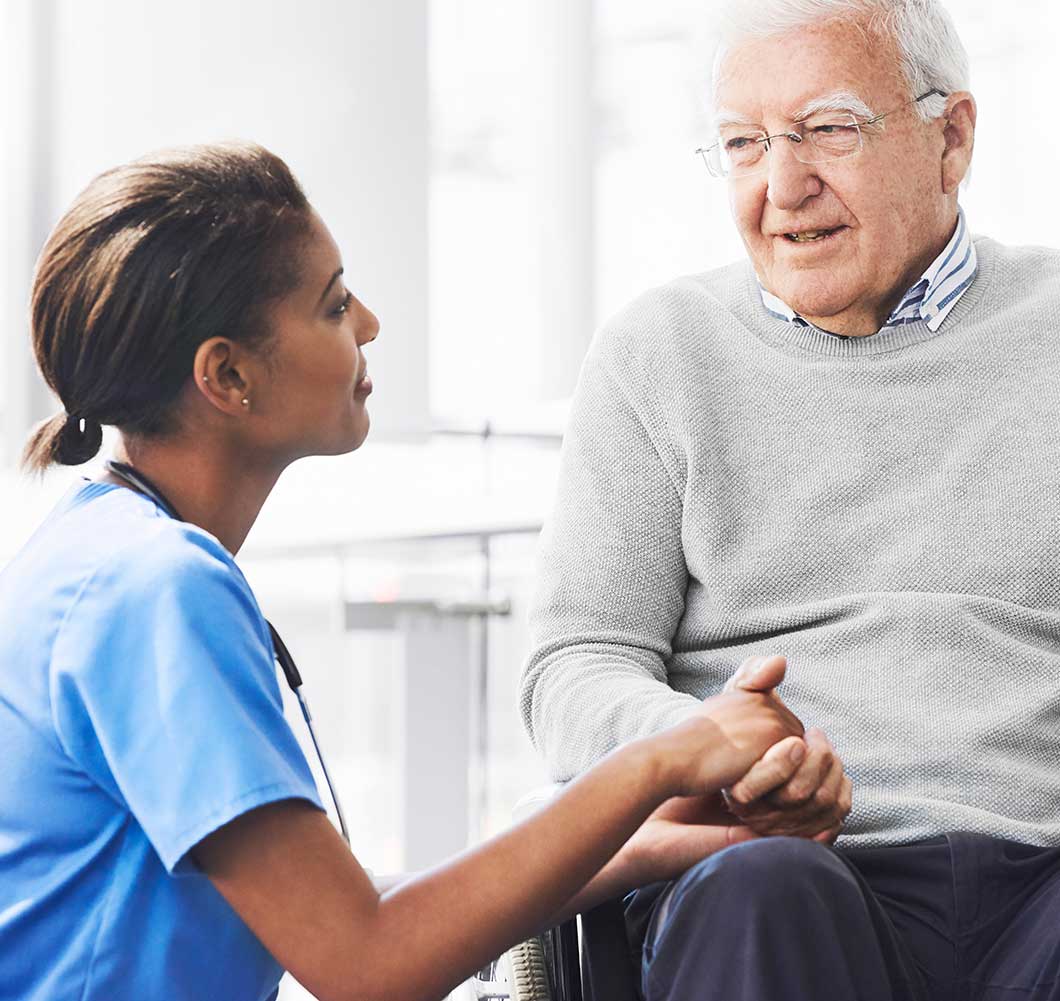 Hospice nurse offering comfort and holding hands with an elderly patient at home, symbolizing dignity and peace in hospice care.