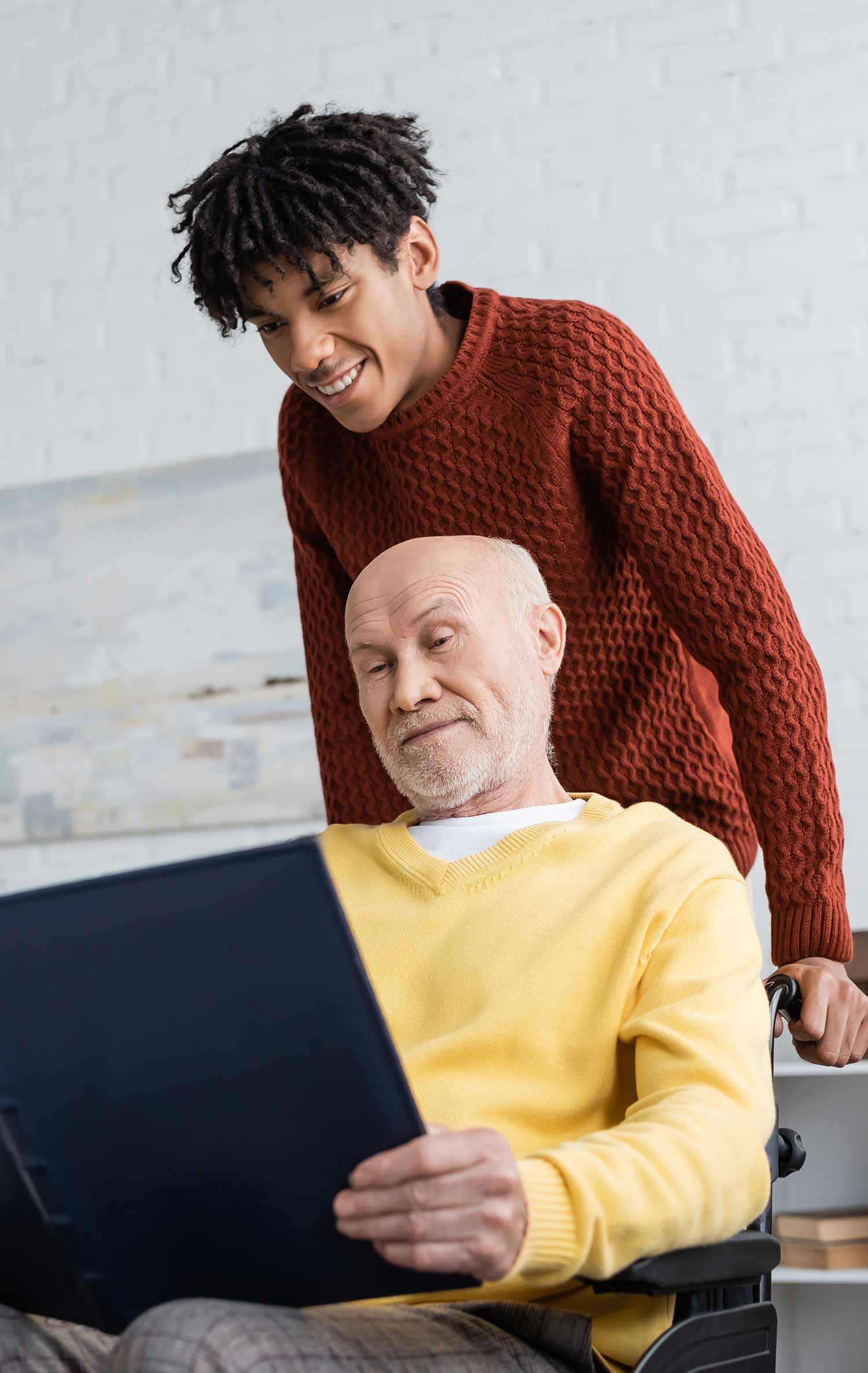 Hospice volunteer supporting an elderly man in a wheelchair, symbolizing companionship and caring support at St. Mary’s Hospice.
